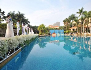 Relax by the serene pool surrounded by lush greenery and palm trees.