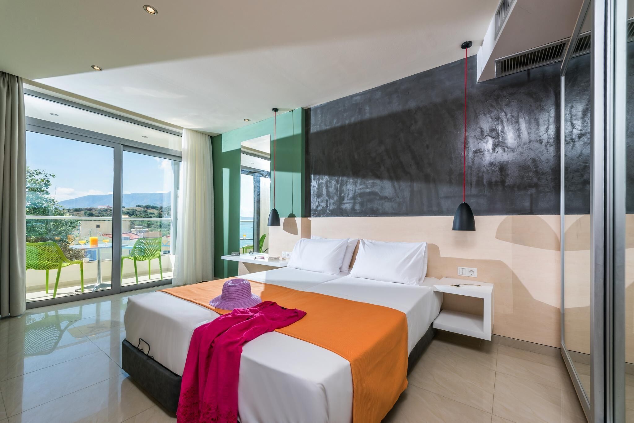 Una habitación de hotel moderna con una cama grande, un balcón con vistas y un diseño minimalista.