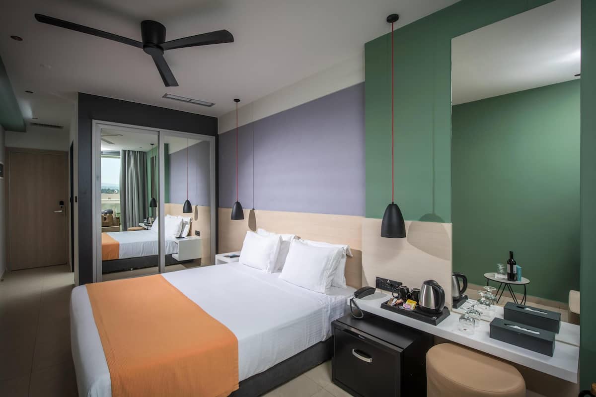 A hotel room with a bed, bedside table, desk, chair, and a ceiling fan.