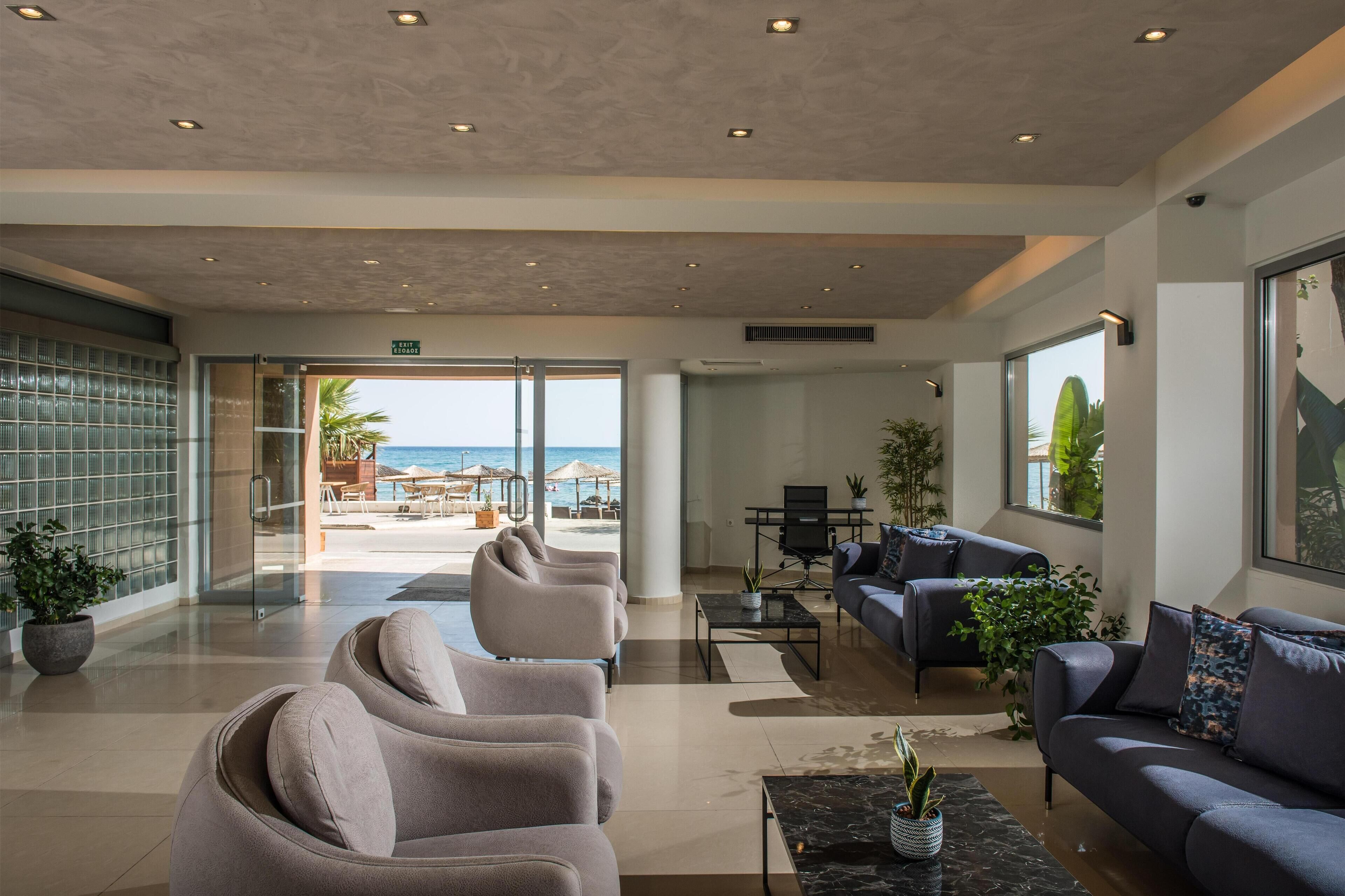 Un vestíbulo moderno con vista a la playa, asientos cómodos y una zona de recepción.