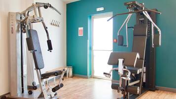 Een sportschool met twee trainingsapparaten, een bank en een deur die naar buiten leidt.