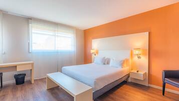 A modern bedroom with a large bed, bedside tables, a desk, and a bench.