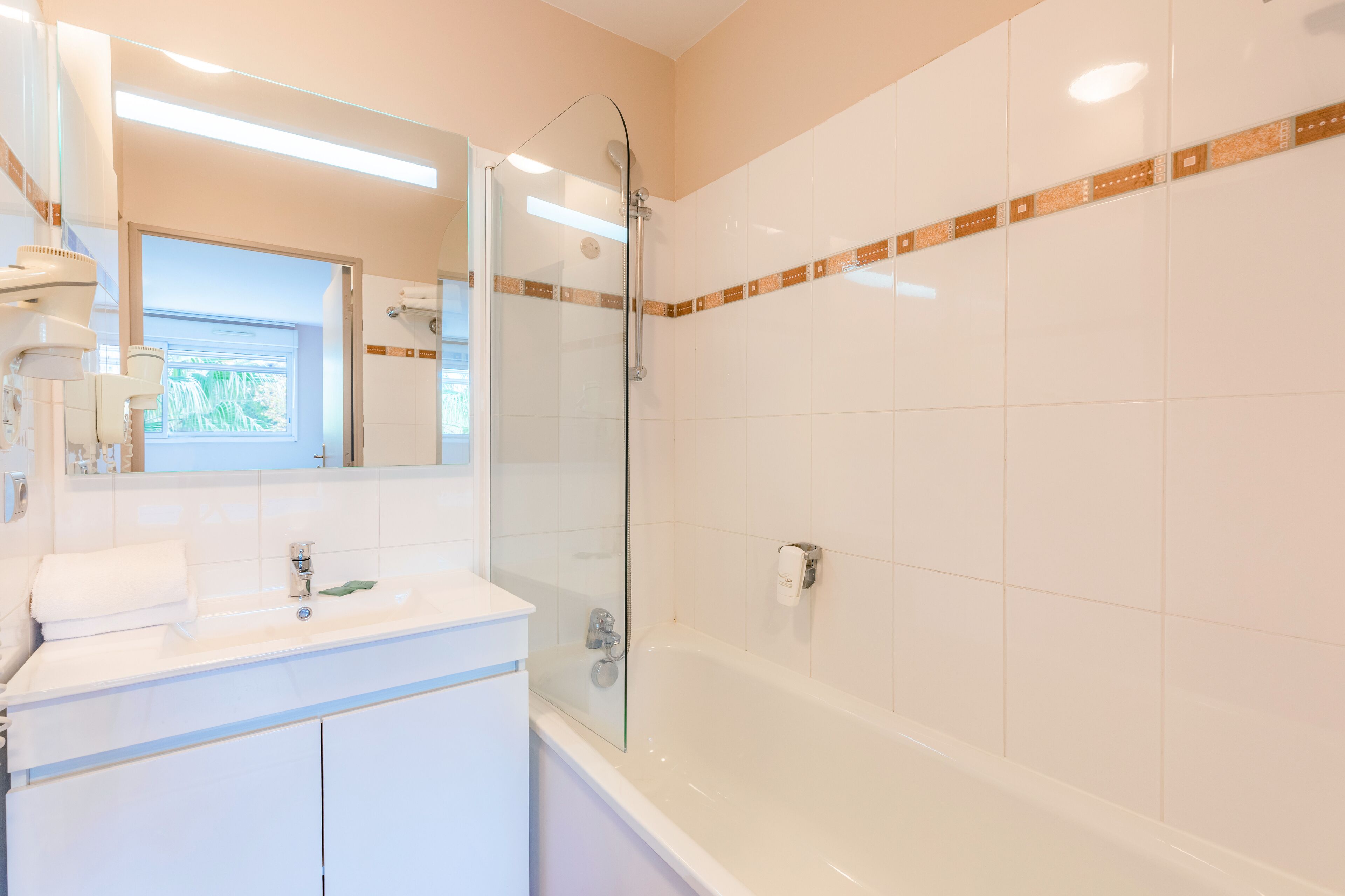 A modern bathroom with a glass-enclosed shower, a white vanity with a mirror, and a bathtub.