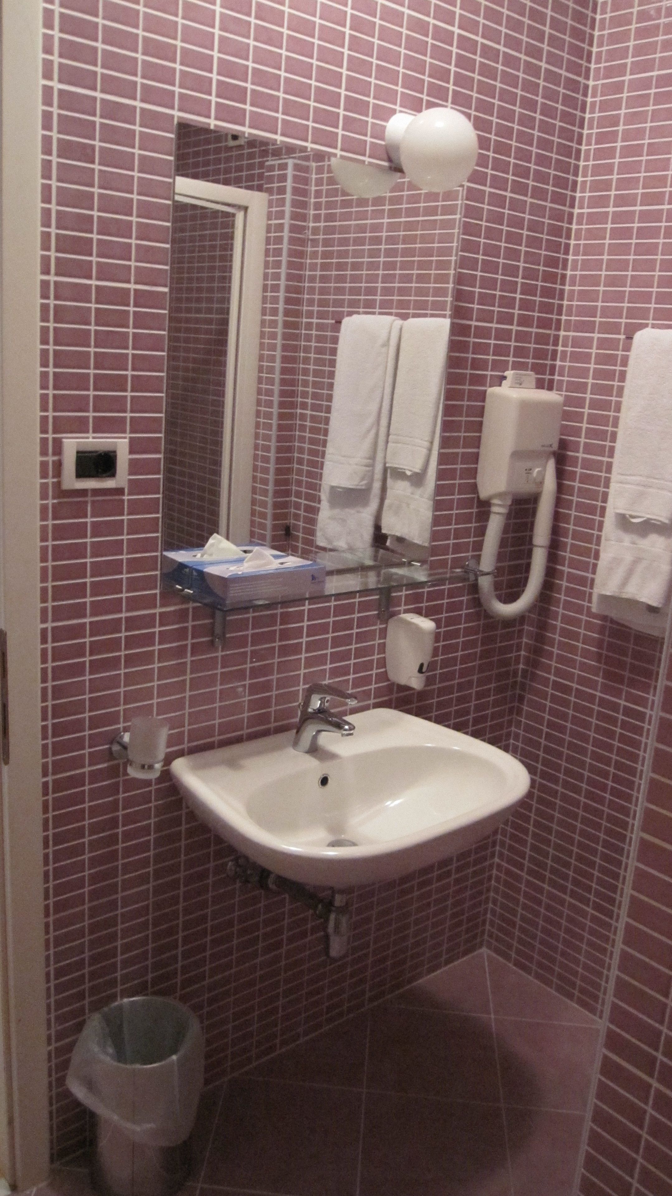 Une salle de bain équipée d’un lavabo, d’un miroir, d’un distributeur de serviettes et d’un sèche-mains.