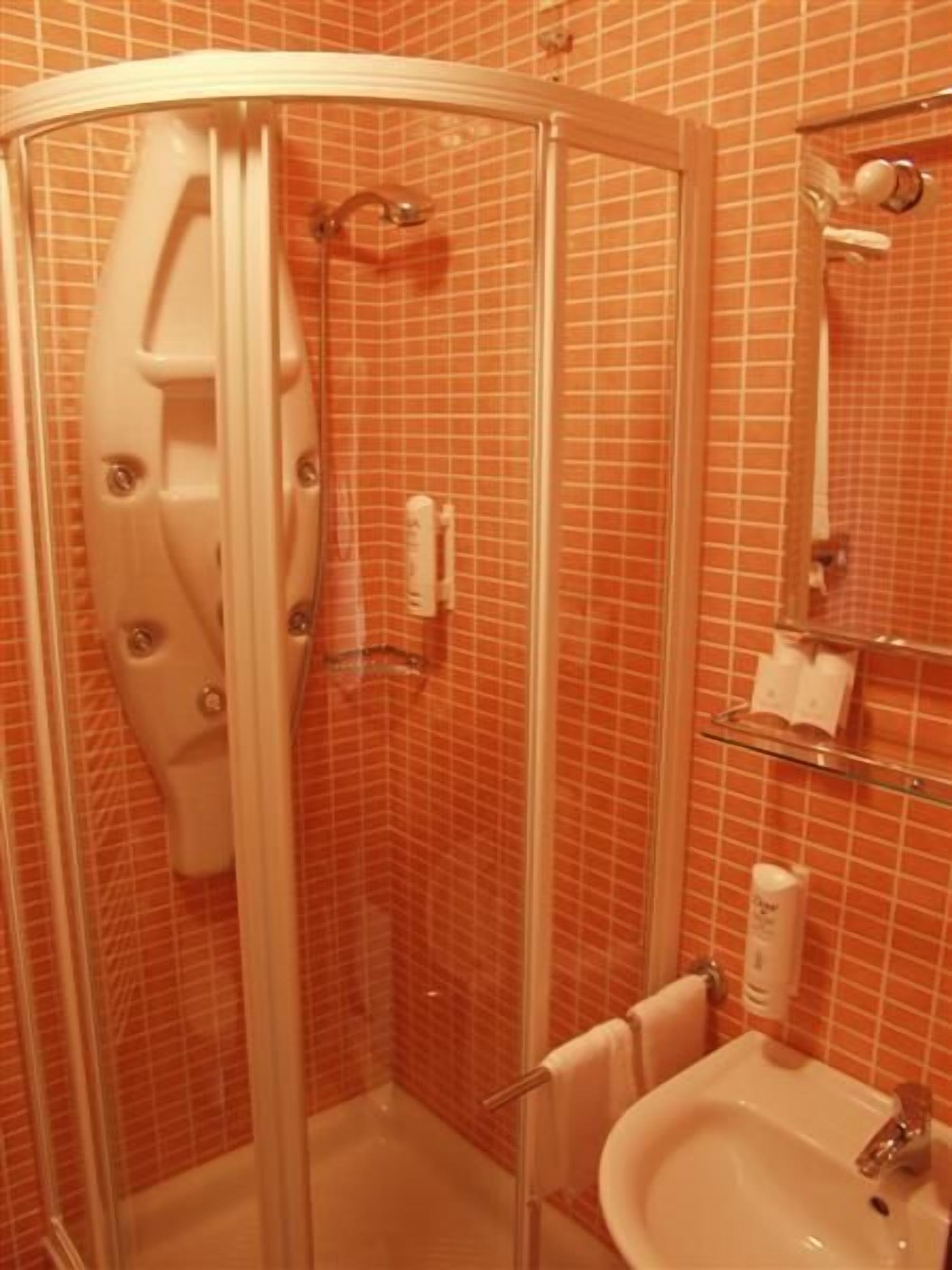 Une salle de bain avec une douche à parois de verre, un lavabo et un miroir.