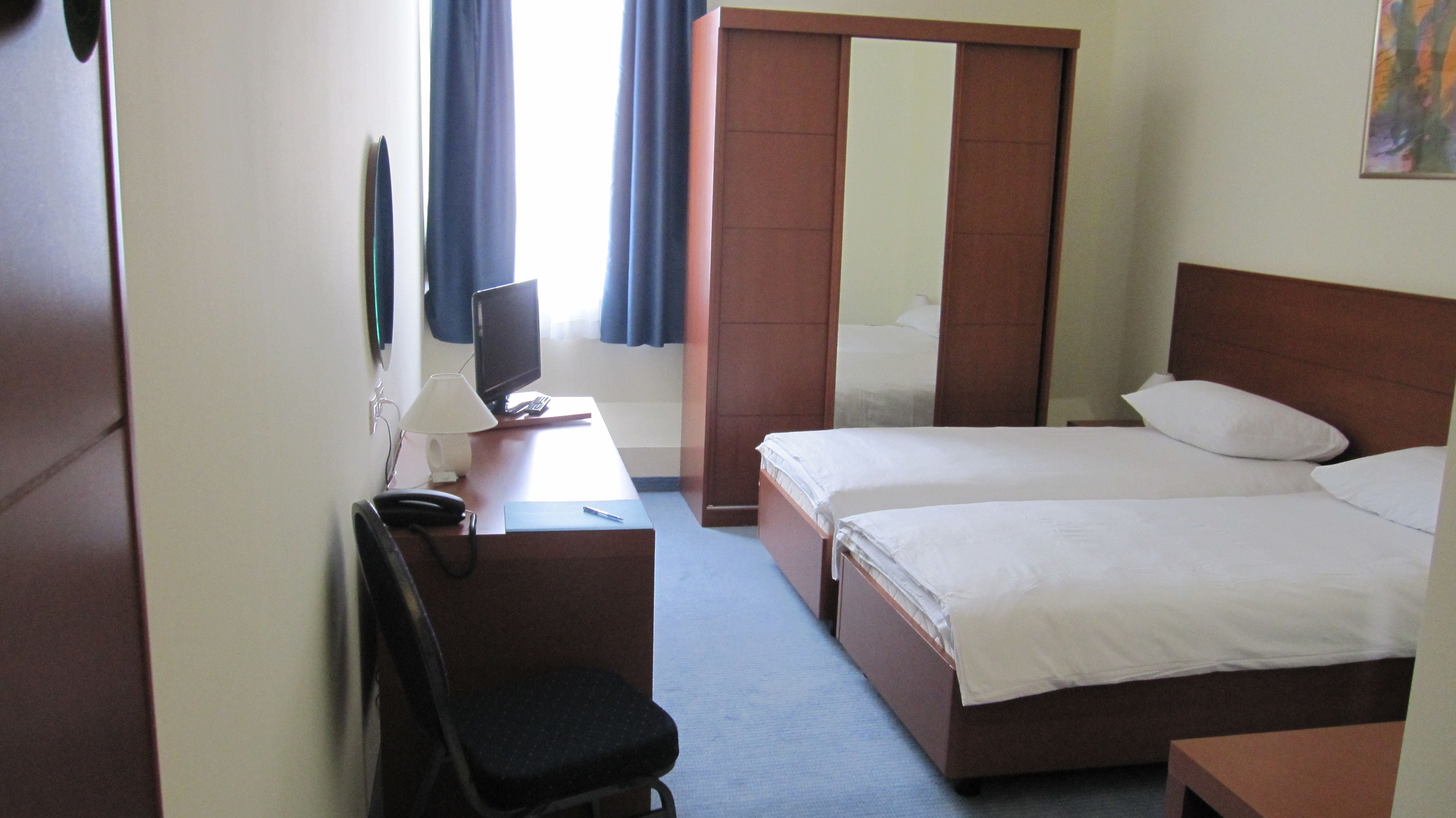 Ein Hotelzimmer mit Schreibtisch, Stuhl, Bett und Fernseher.