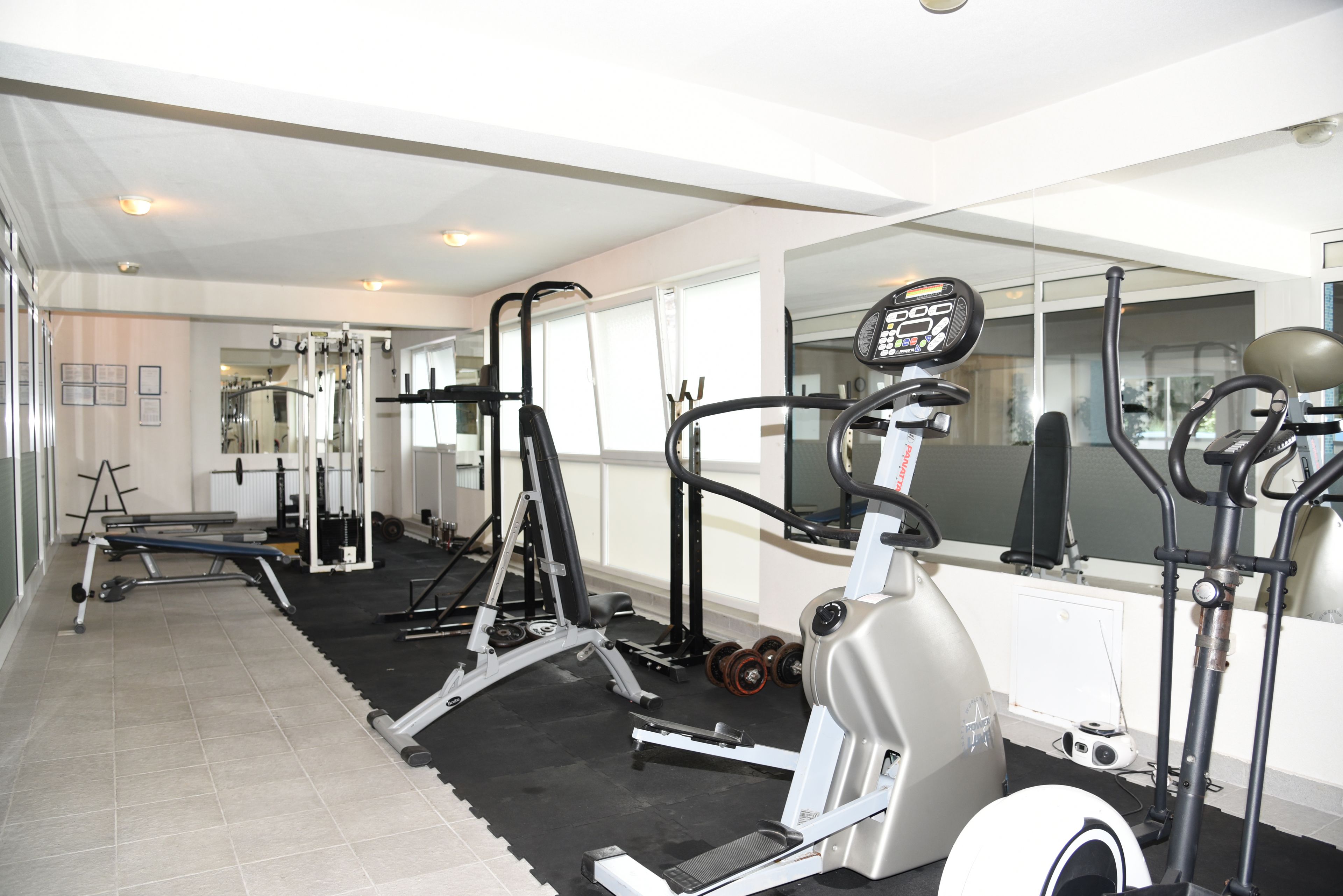 A gym with various exercise equipment, including treadmills and weight machines, and a large mirror on one wall.