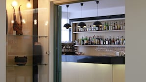 A bar area with shelves of bottles and glasses, a counter, and hanging pendant lights. - Hotel Califfo (Quartu Sant'Elena)