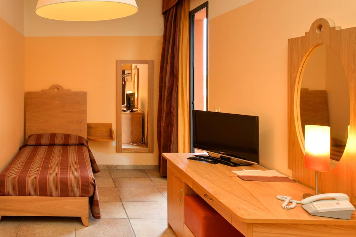Une chambre d’hôtel comprenant un lit, un bureau avec un téléphone, une télévision et un miroir.