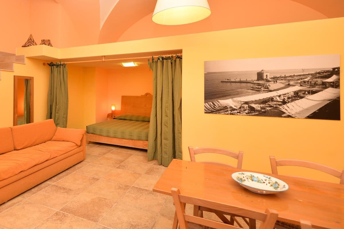 Une pièce comprenant un lit, un canapé, une table à manger et un tableau au mur.