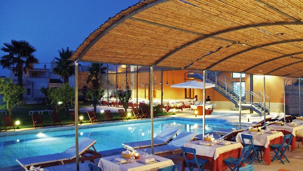 Un restaurant situé au bord de la piscine, avec une terrasse, un espace couvert et un escalier menant à un niveau supérieur.