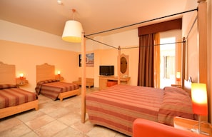 A hotel room with a large bed, two smaller beds, a desk with a TV, a mirror, and a window with curtains. - Il Tabacchificio Hotel (Gagliano del Capo)