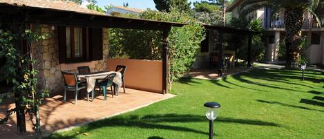 A patio area with a stone wall, a table with chairs, and a pergola.
