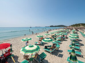 En la playa, playa de arena blanca, camastros y sombrillas 