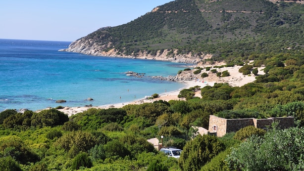 A coastal landscape with a beach, rocky cliffs, and dense greenery. - Green Village Resort (Villasimius)
