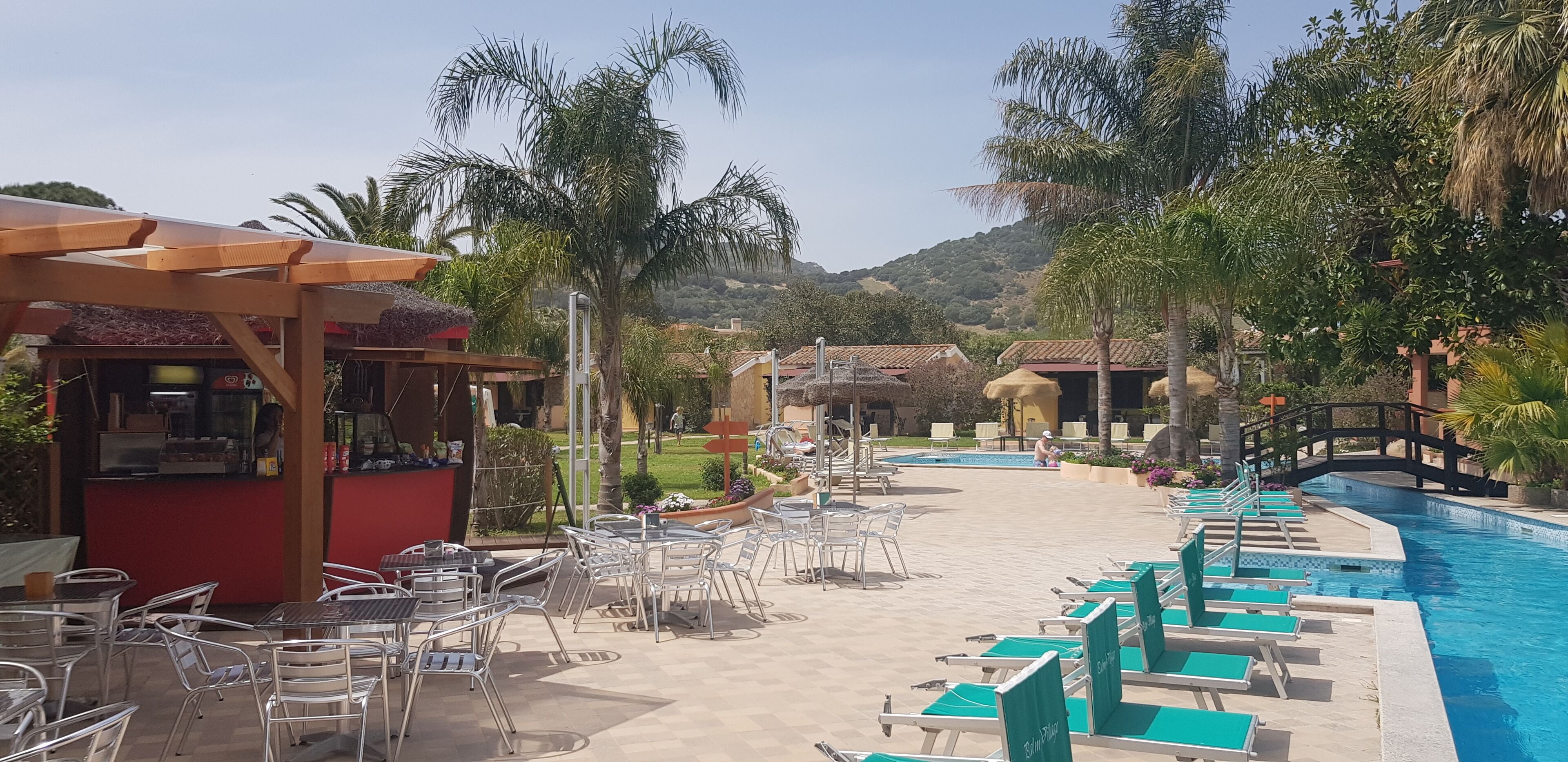 Zona d'una piscina amb gandules i un bar.