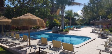 Una piscina al aire libre de temporada, sombrillas, tumbonas