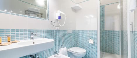 A bathroom with a sink, bidet, toilet, and shower.