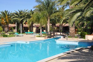 Una piscina al aire libre de temporada, sombrillas, tumbonas