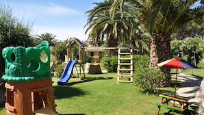 A playground with a slide, climbing structures, and a picnic table. - Green Village Resort (Villasimius)
