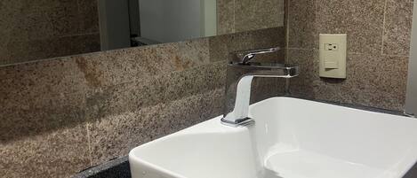 A bathroom with a white sink, a mirror, and a granite countertop.