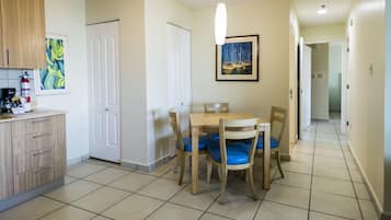 Un coin repas avec une table et des chaises en bois, une machine à café et un tableau encadré accroché au mur.