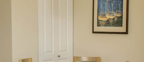 Un comedor con una mesa y sillas de madera, una puerta blanca y un cuadro en la pared.