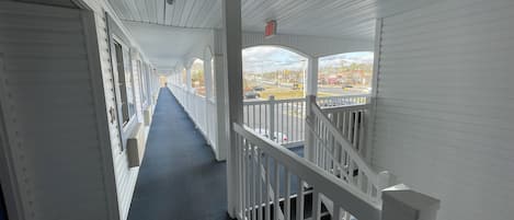 A corridor with white railings and a view of the outside.