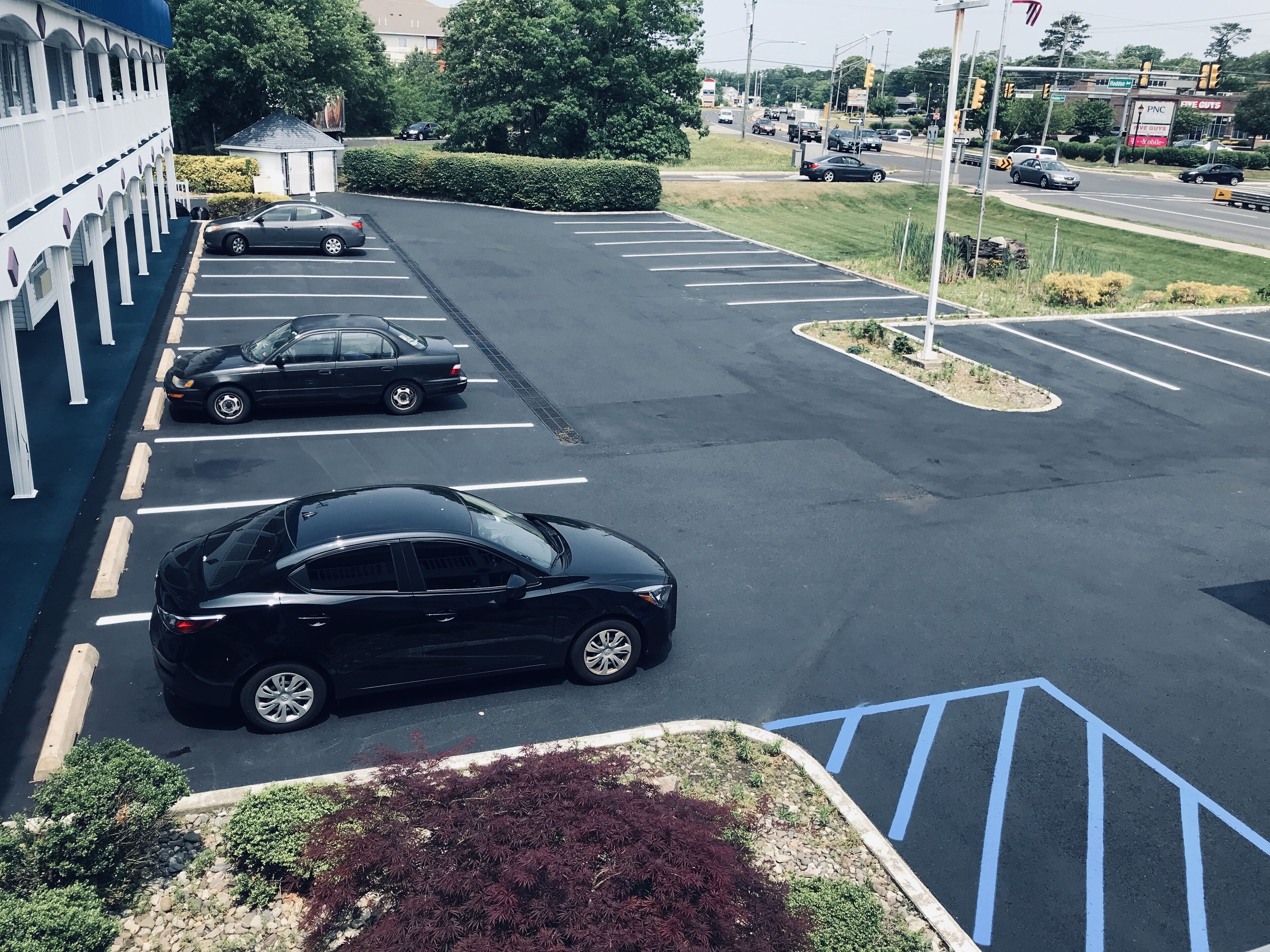 Un estacionamiento con varios automóviles y un edificio de fachada blanca y columnas.