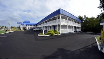 Un motel con techo azul y fachada blanca, que cuenta con un patio central y varios balcones.