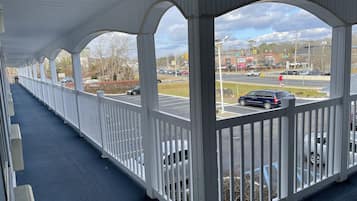 A covered outdoor area with white railings and a view of a parking lot and road.