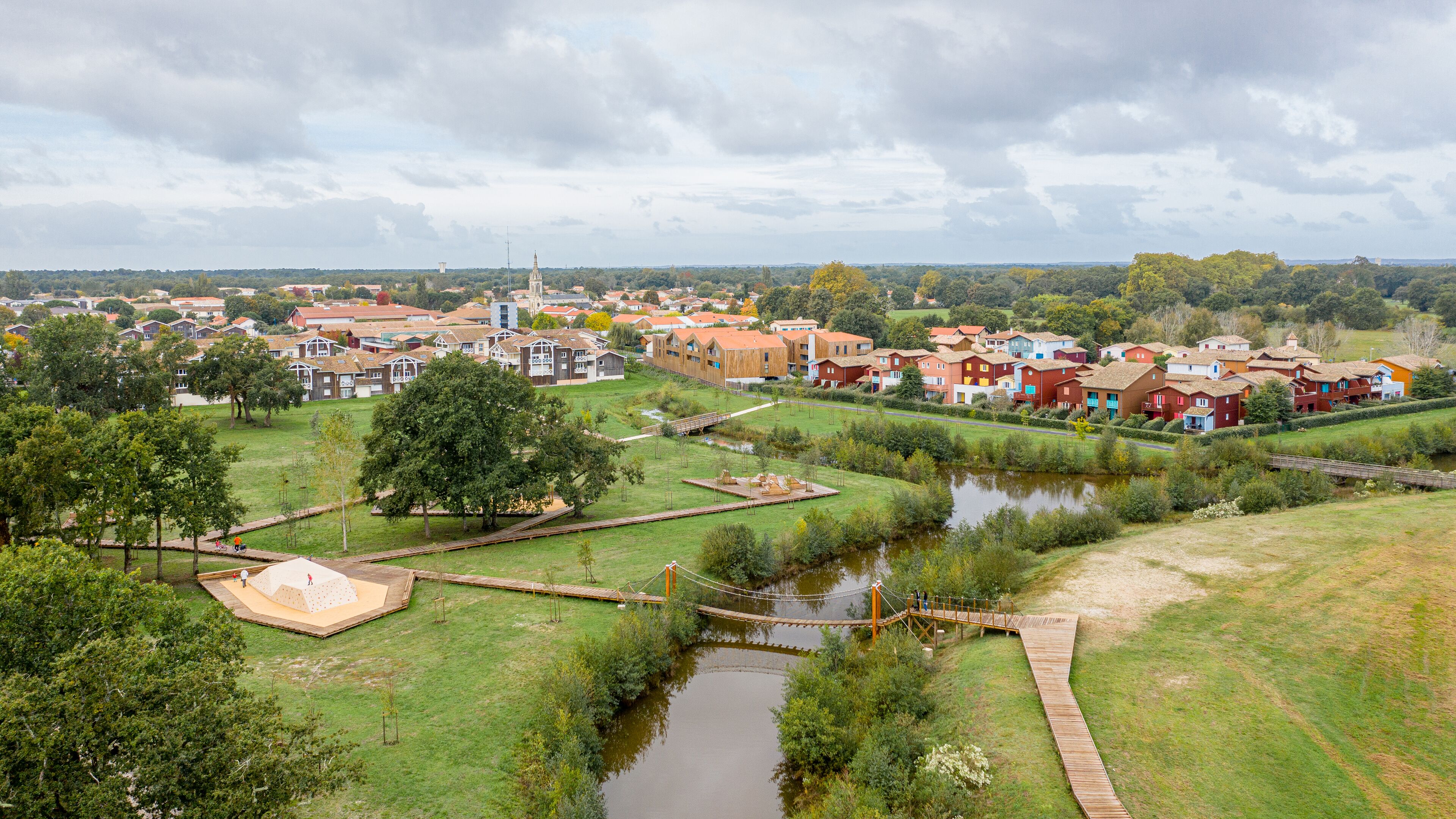 Un barrio residencial con casas, un río pequeño y un puente.