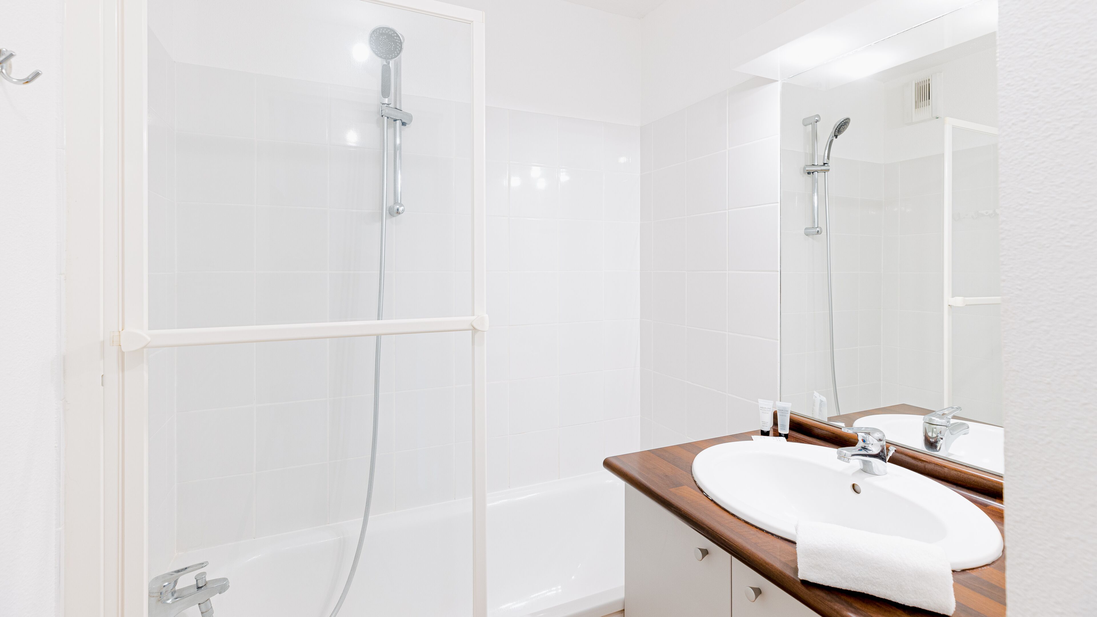 A modern bathroom with a glass-enclosed shower, a wooden vanity with a white sink, and a large mirror.
