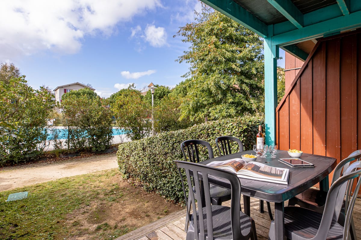 A patio with a table and chairs, a bottle of wine, and a bowl of fruit.