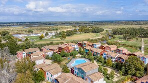 A residential area with colorful houses, a swimming pool, and a marina with boats. - Madame Vacances Residence Les Rives Marines (Le Teich)