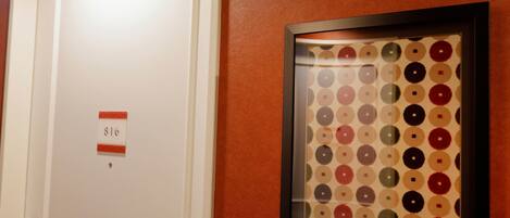 A door with a room number sign and a framed artwork on the wall.