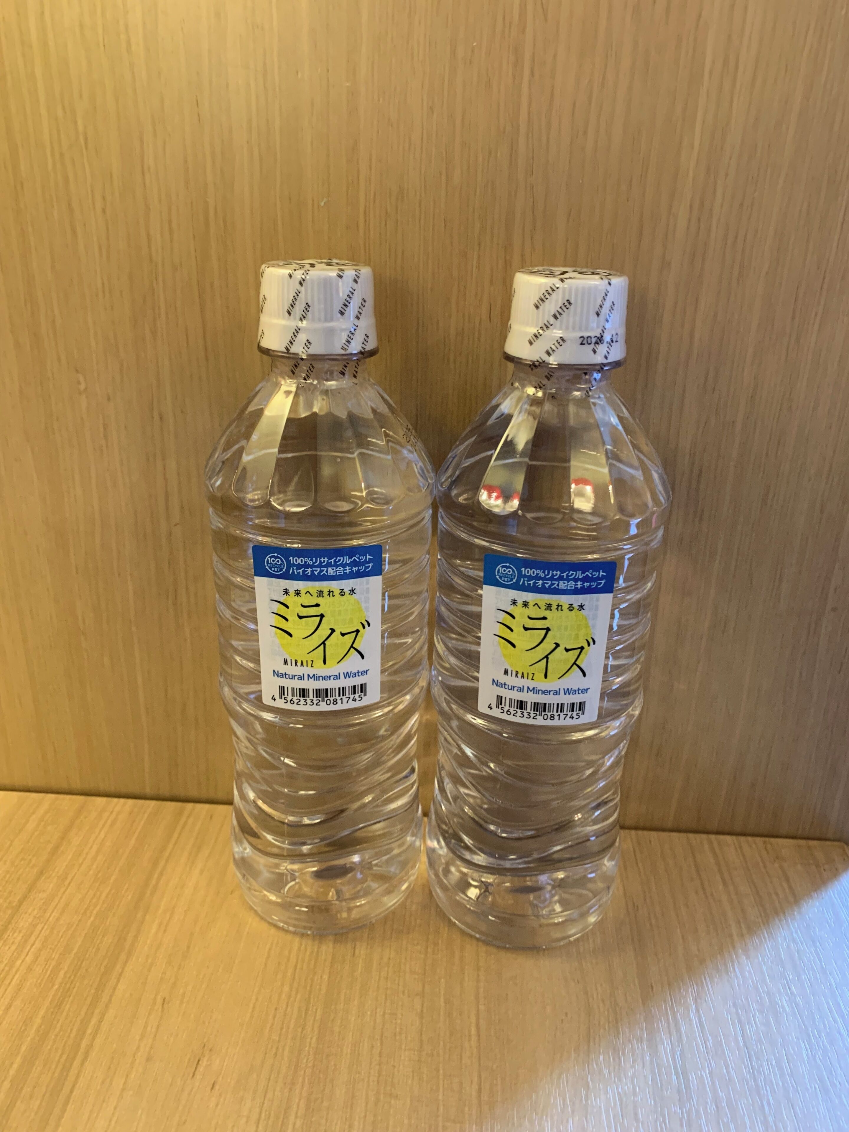 Dos botellas de agua con la etiqueta "MIRAIZ" sobre una superficie de madera.
