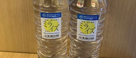 Deux bouteilles d’eau portant l’étiquette « MIRAIZ » sont posées sur une surface en bois.