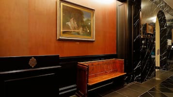 Un vestíbulo con un banco de madera, un cuadro enmarcado en la pared y un suelo de mármol.