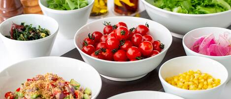 Various bowls containing different ingredients like tomatoes, lettuce, and corn, suggesting a food preparation setting.