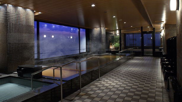 Area piscina interna moderna con pavimento a scacchi, barriera in vetro e vista sul cielo notturno.