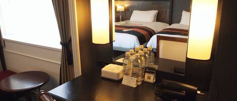 A hotel room with a bed, bedside lamps, a desk with a telephone, a mirror, and a window with curtains.