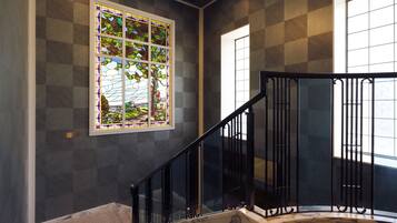 A staircase with black railings and a stained glass window depicting a landscape.