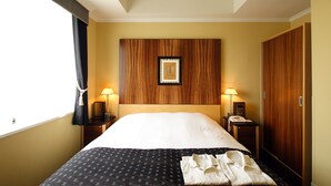 Ein Hotelzimmer mit einem großen Bett, einem Holzkopfende, zwei Nachttischen mit Lampen, einem Kleiderschrank und einem gerahmten Bild an der Wand.