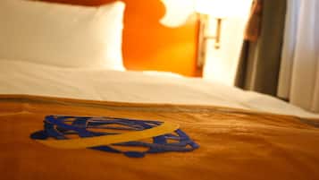 Un lit avec des draps blancs et un objet jaune et bleu posé sur la couverture.