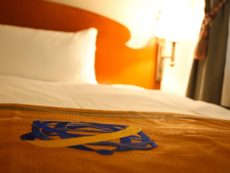 Una cama con sábanas blancas y un objeto amarillo y azul sobre la colcha.