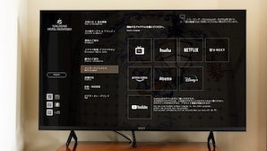 Een televisie bevestigd aan een houten kastje, met een menu-interface die diverse streamingdiensten toont.
