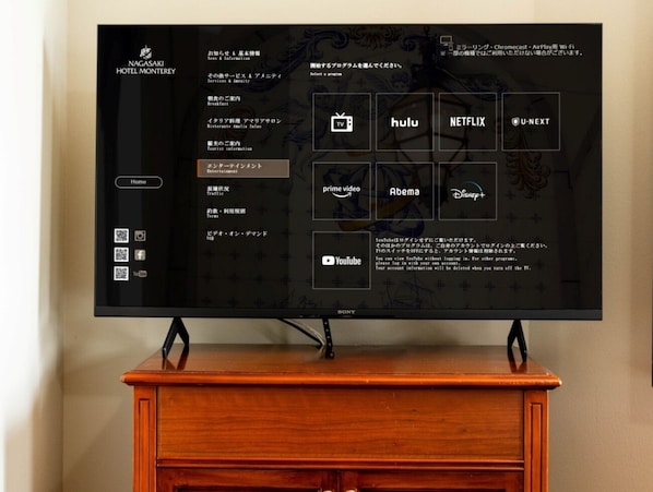 Un téléviseur fixé sur un meuble en bois, dont l’interface de menu affiche différents services de diffusion en continu.