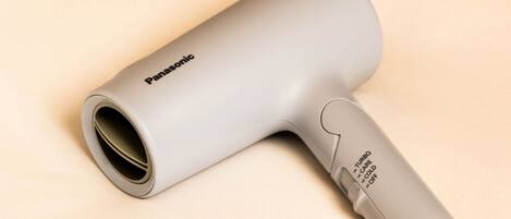 A Panasonic hair dryer with a handle and a cylindrical body, placed on a light-colored surface.