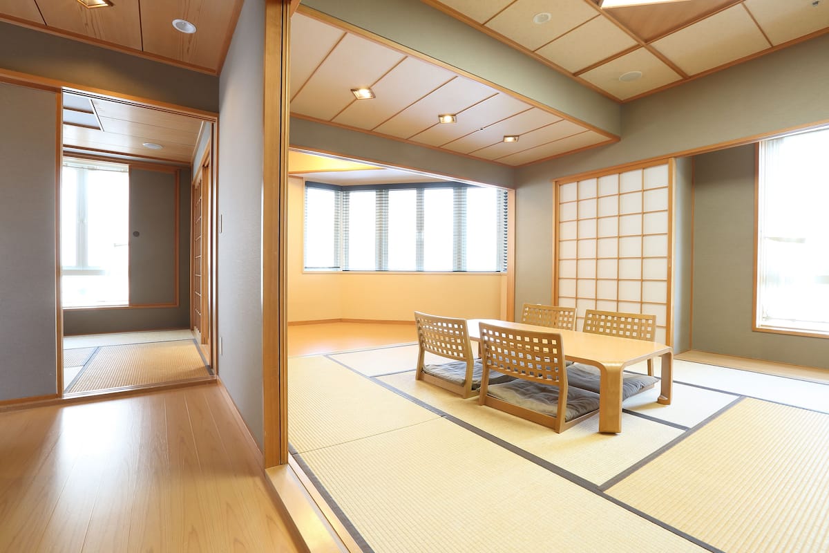 A traditional Japanese room with tatami flooring, a low table with sliding doors, and a shoji screen.